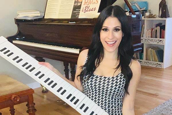 Krystle Rose holding a white Carry-On piano